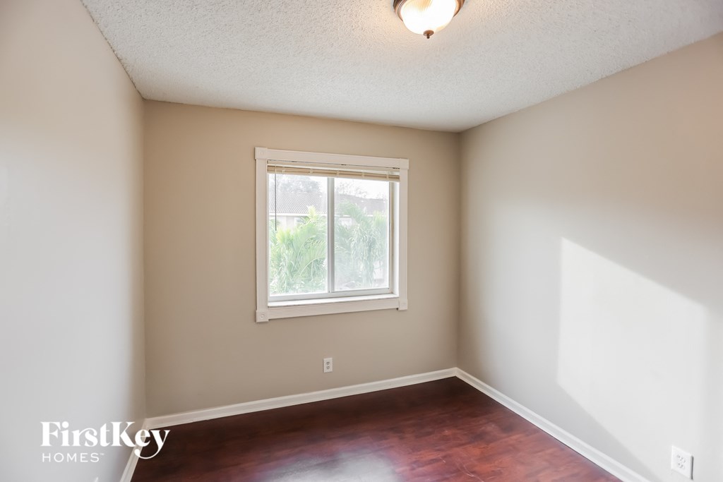 an empty room with a window and wooden floors
