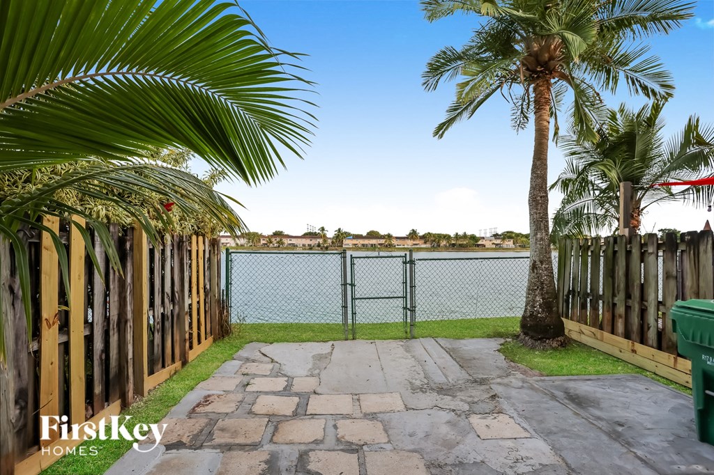 a fenced in yard with a lake and palm trees