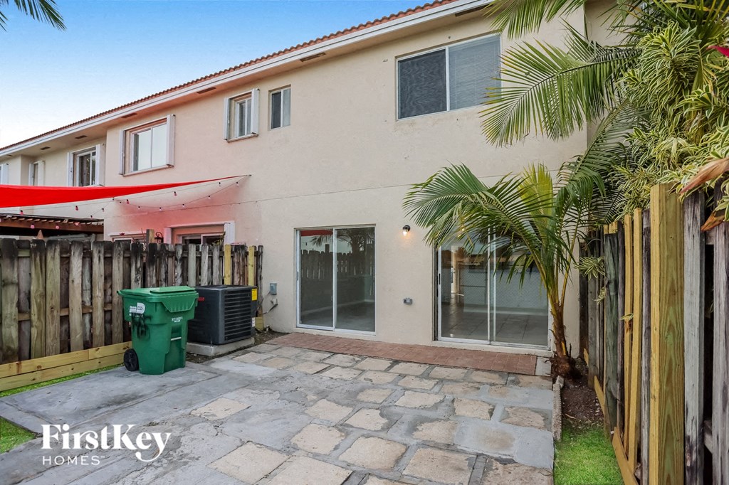 a white house with a yard and a green trash can