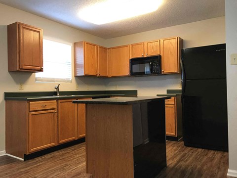 A kitchen with wooden cabinets and a black refrigerator.