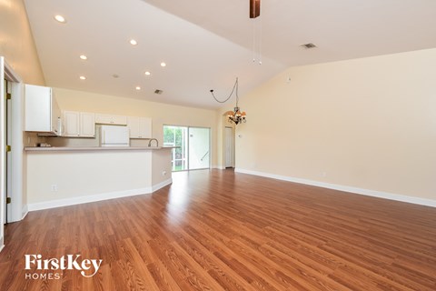 an empty living room and kitchen with wood flooring