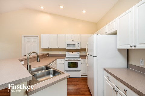 a kitchen with white cabinets and appliances and a sink