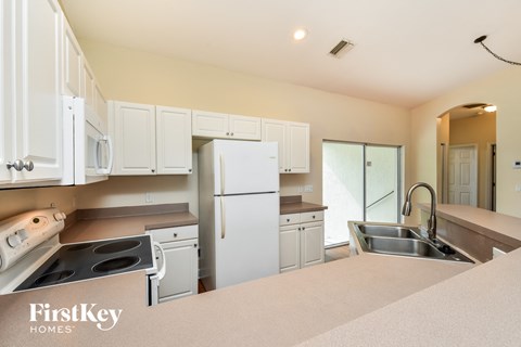 a kitchen with white cabinets and a white refrigerator and sink