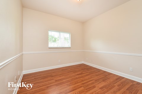 a bedroom with wood flooring and a window