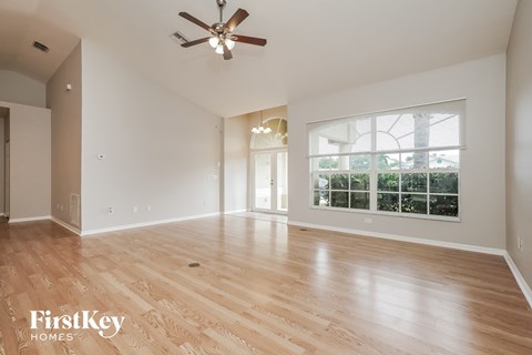 A spacious room with wooden flooring and a ceiling fan.