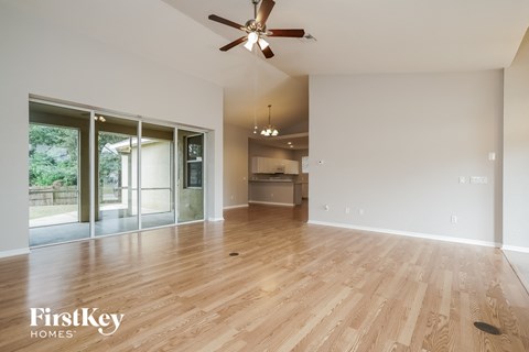 A spacious room with wooden flooring and a ceiling fan.