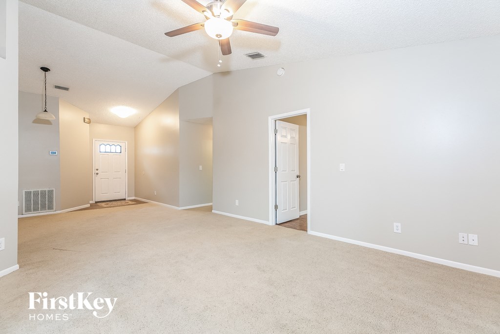 an empty living room with a ceiling fan and a white door