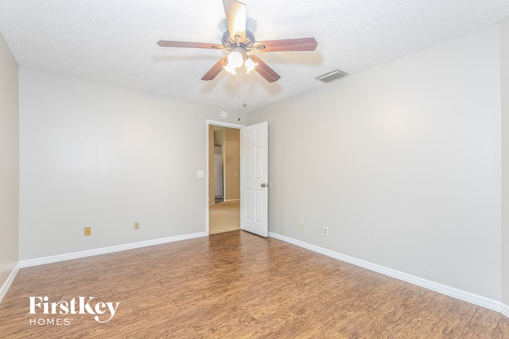 a spacious living room with white walls and a ceiling fan