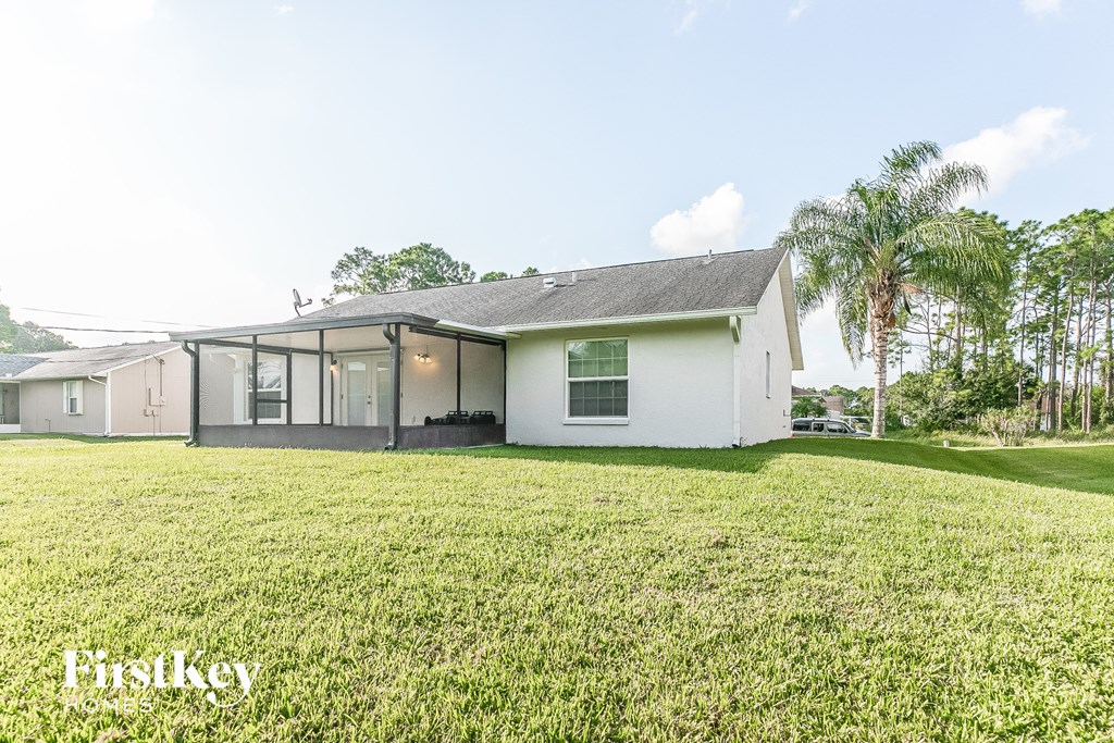 a white house with a grass yard and palm trees
