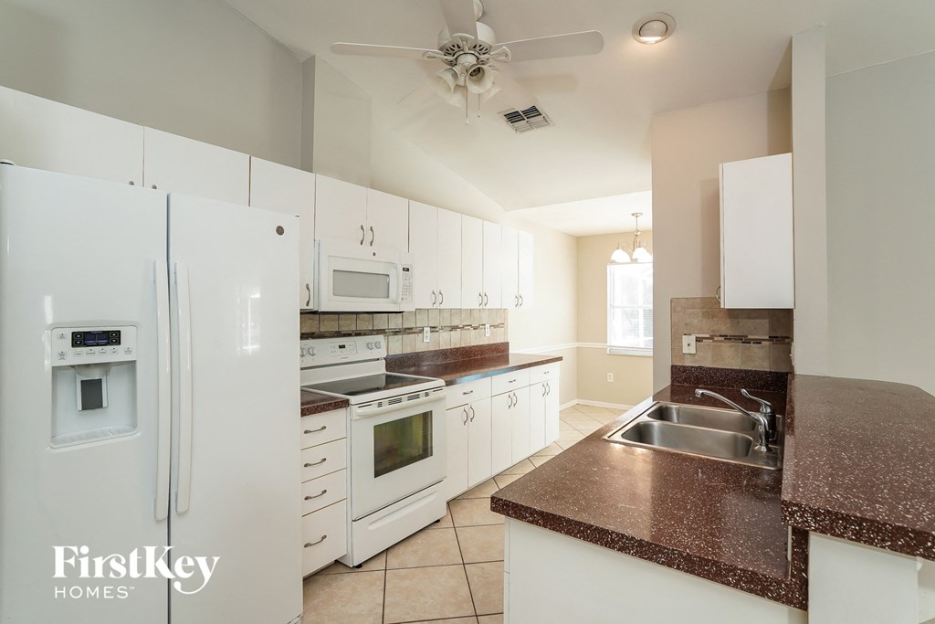 A kitchen with white appliances and a brown countertop.