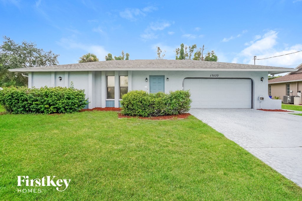 A white house with a garage door and a driveway in front.