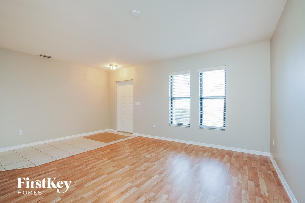 A room with wooden flooring and a window with blinds.