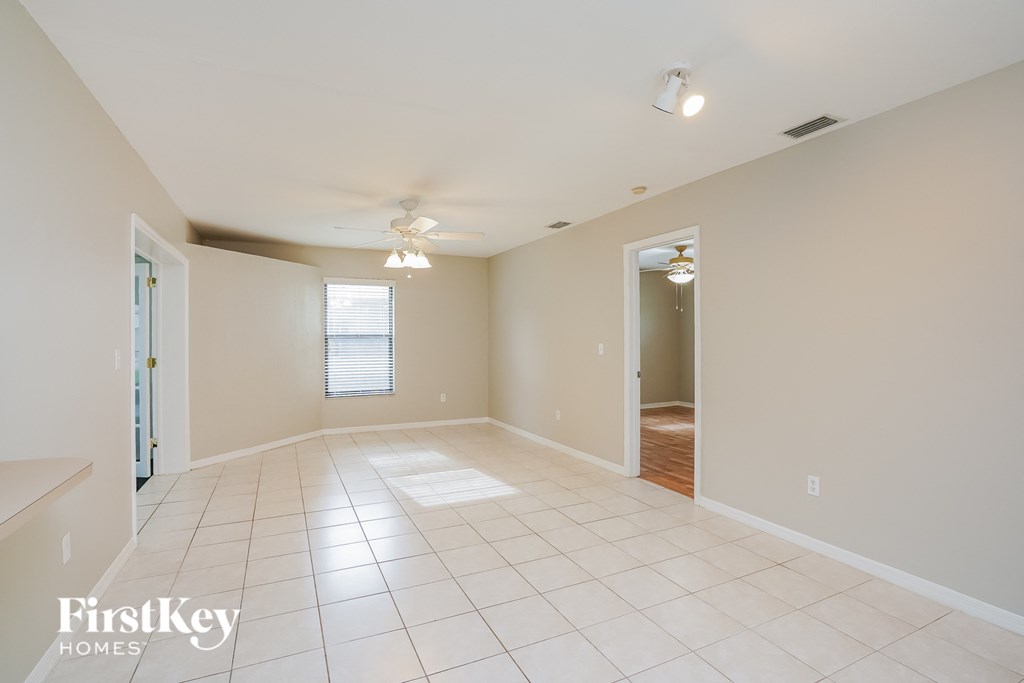 A spacious empty room with a fan and a doorway leading to another room.