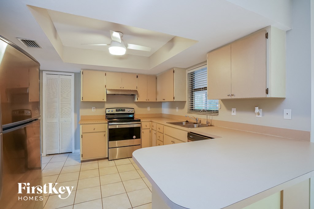 A kitchen with a white counter top and wooden cabinets.