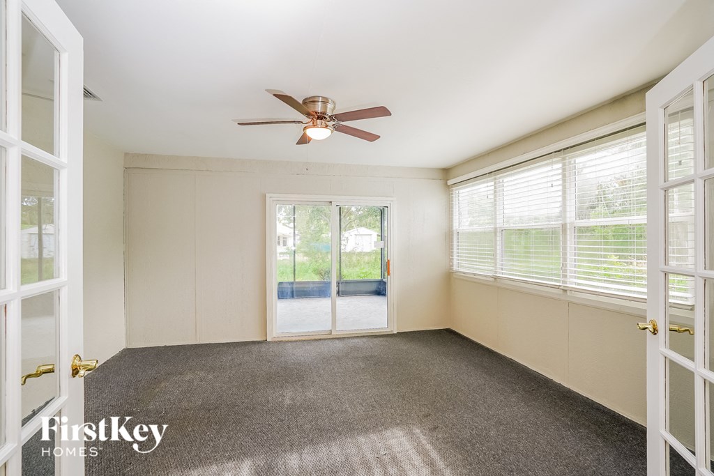 A room with a ceiling fan and sliding glass doors.