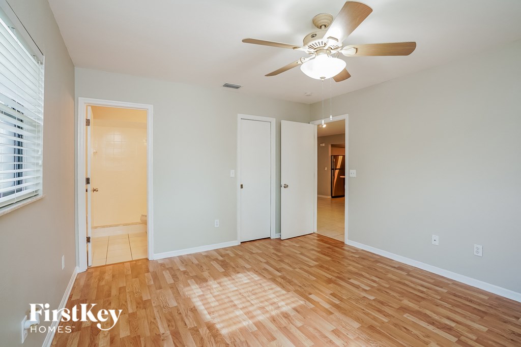 A room with a ceiling fan and wooden floors.