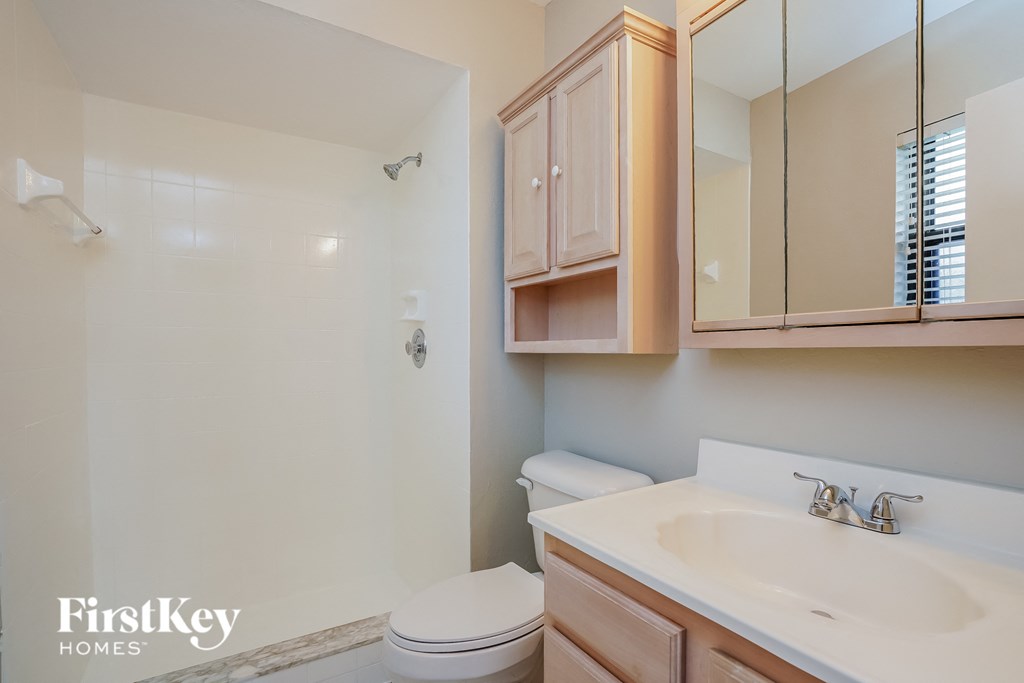 A bathroom with a toilet, sink, and mirror.