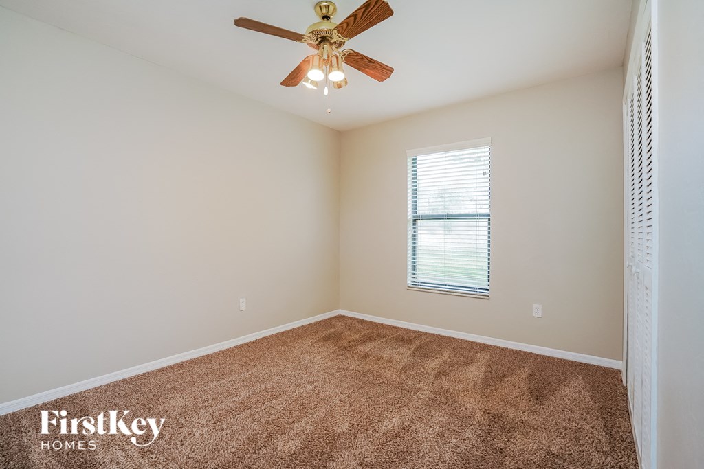 A room with a ceiling fan and a window with blinds.