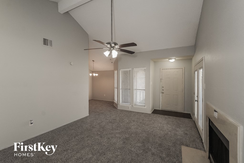 a spacious living room with a ceiling fan and a door to a bedroom