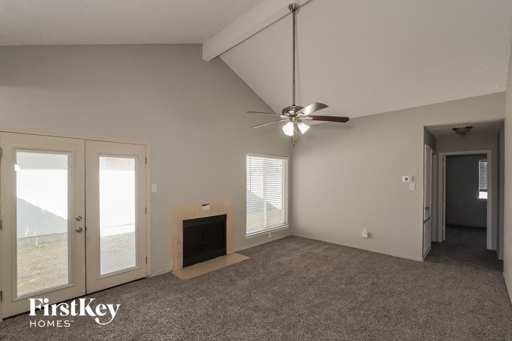 an empty living room with a fireplace and a ceiling fan