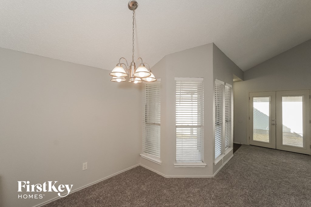 the living room of an empty house with windows and a chandelier