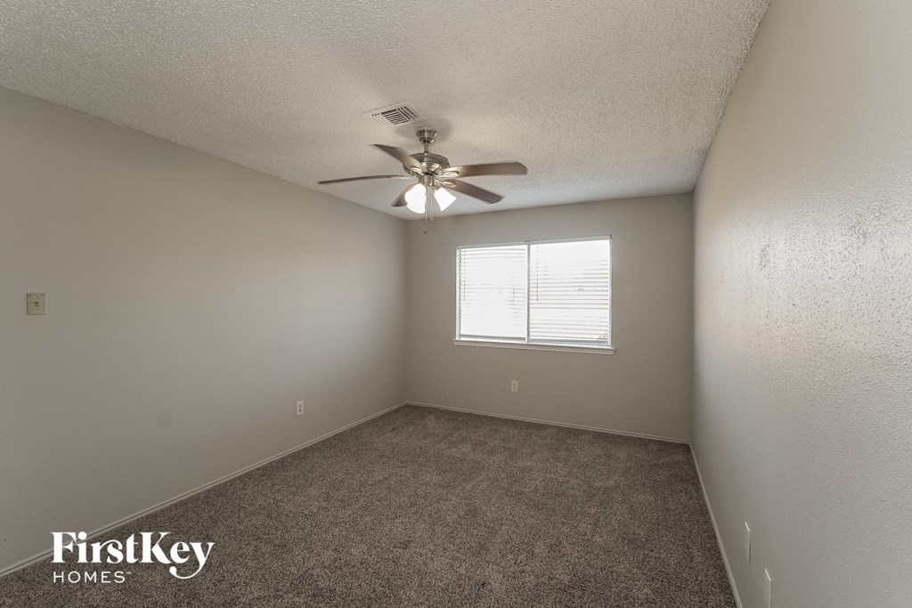 an empty room with a ceiling fan and a window