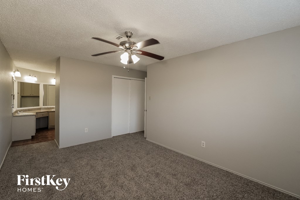 the spacious living room with ceiling fan and carpeting