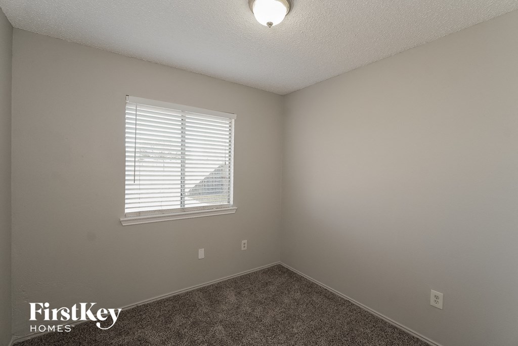 a bedroom with a window and a carpeted floor