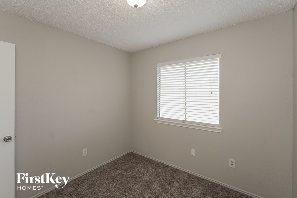 a bedroom with a window and a carpeted floor