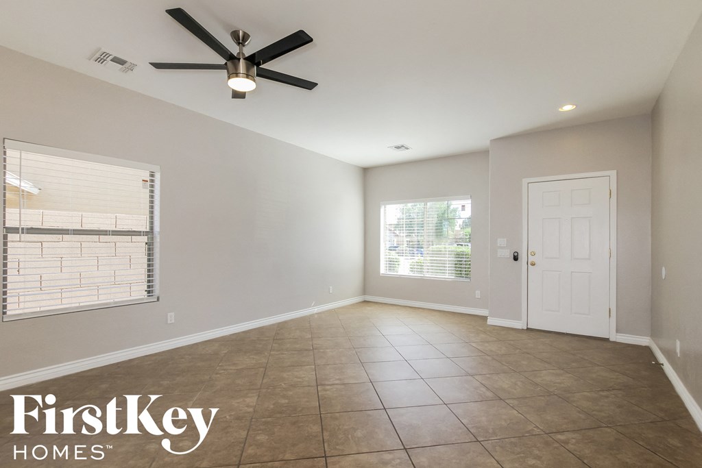 an empty living room with a ceiling fan and a window