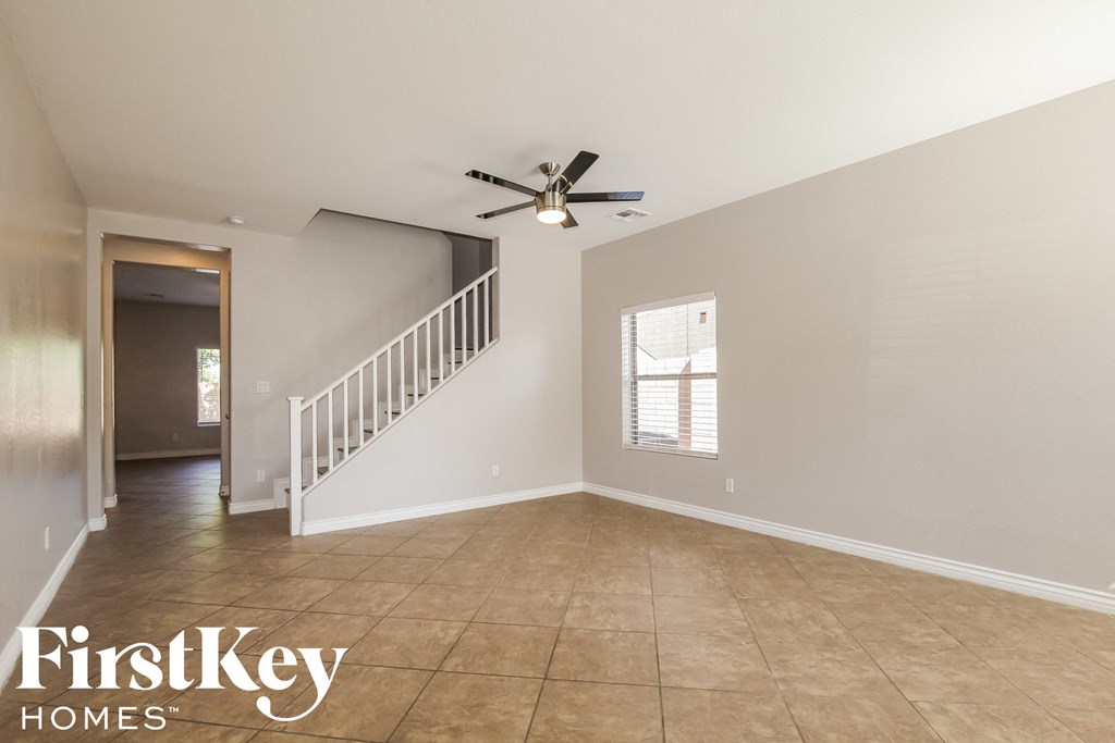 an empty living room with a staircase and a ceiling fan