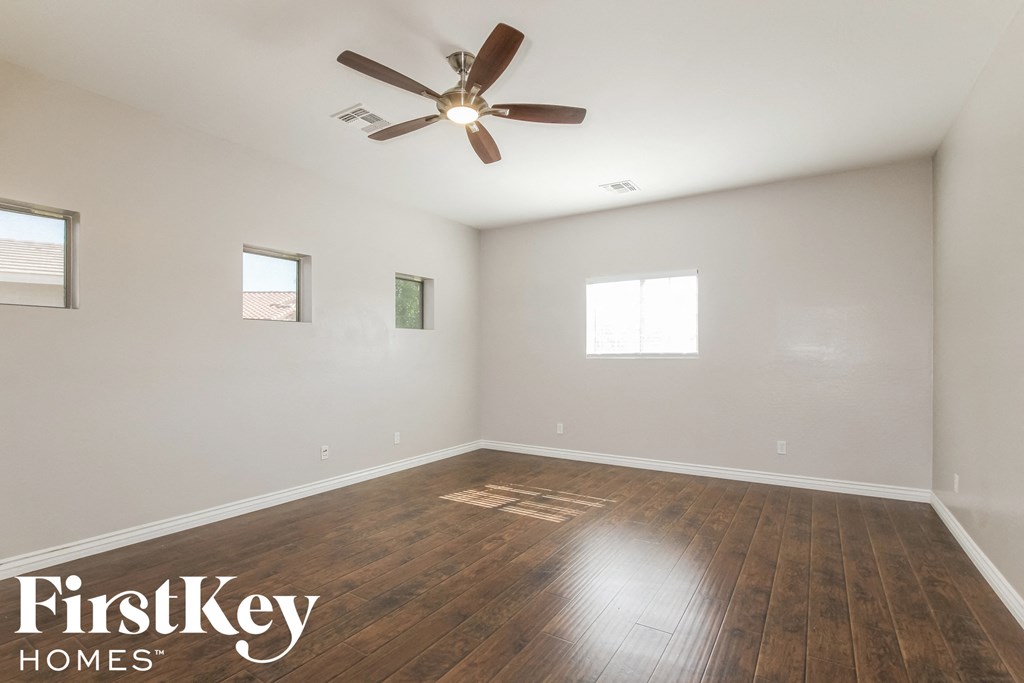 the spacious living room with hardwood flooring and a ceiling fan