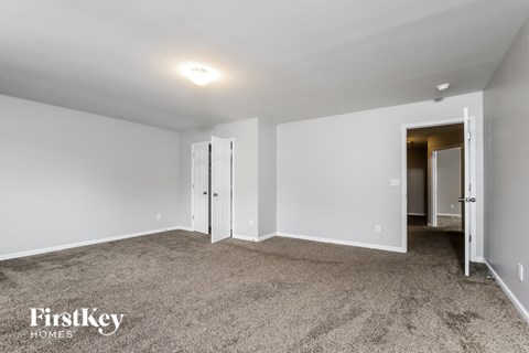 a bedroom with white walls and carpet and a door to a hallway