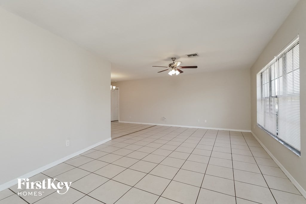 A spacious room with a ceiling fan and tiled floor.