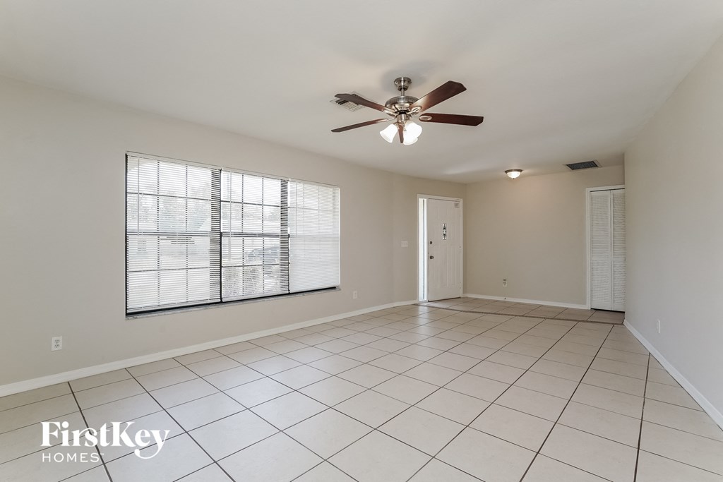 A spacious room with a ceiling fan and large windows.