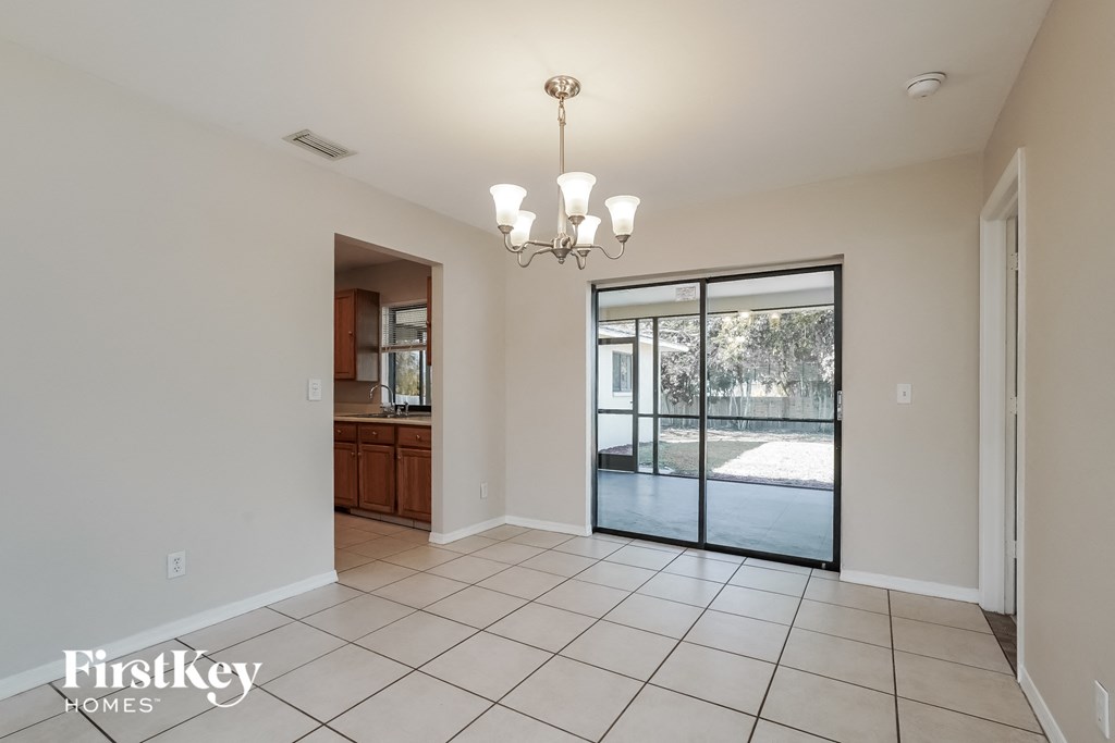 A spacious room with a chandelier and sliding glass doors.
