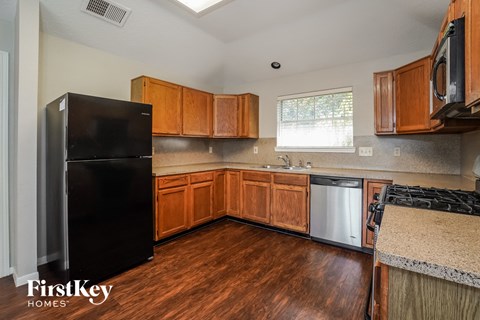 A kitchen with wooden cabinets and a black fridge.