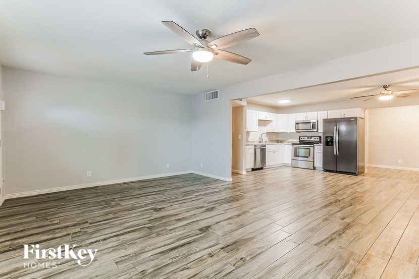 an empty living room and kitchen with a ceiling fan