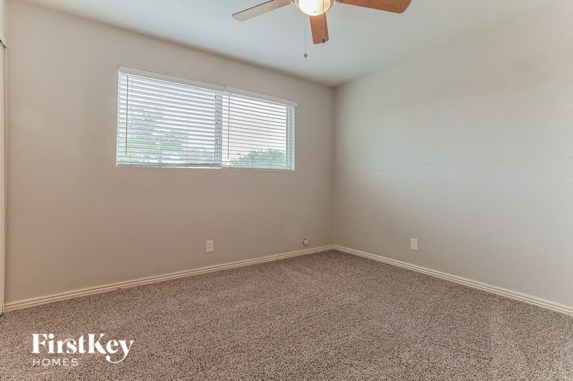 an empty room with a window and a ceiling fan