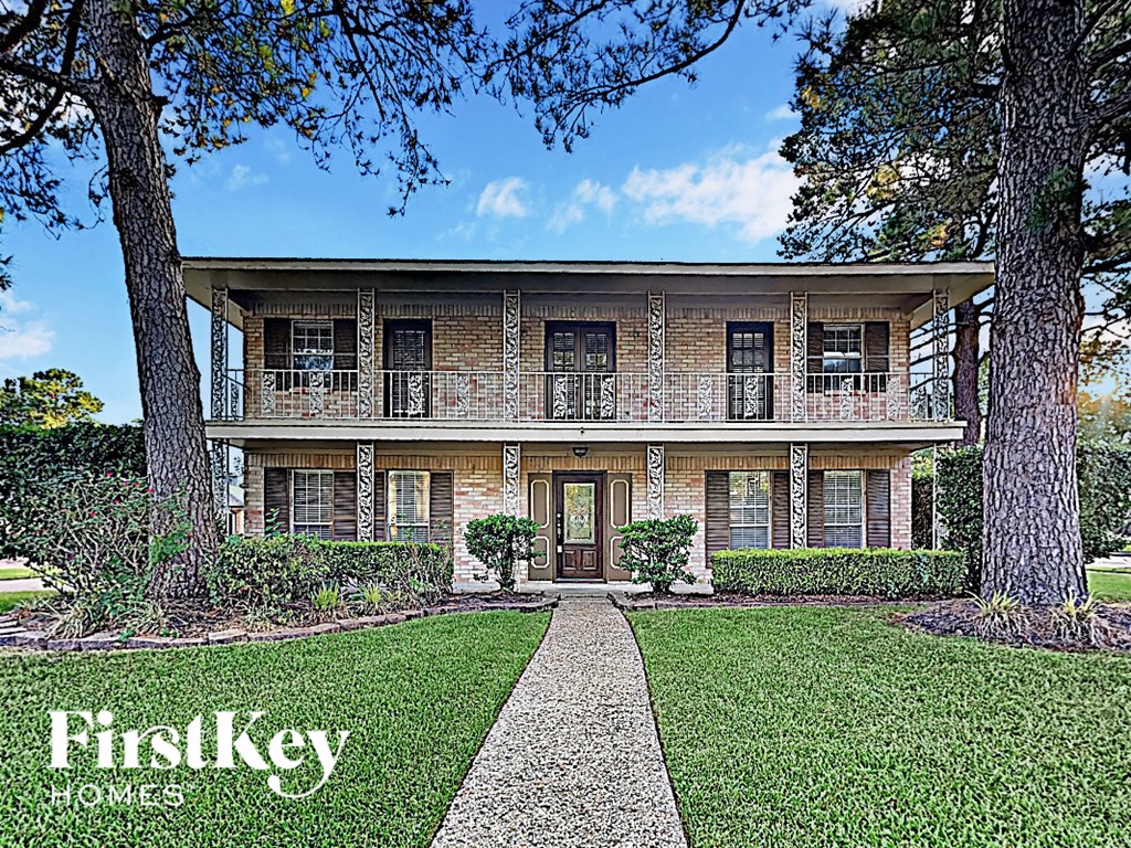 the front of a brick house with trees and a sidewalk