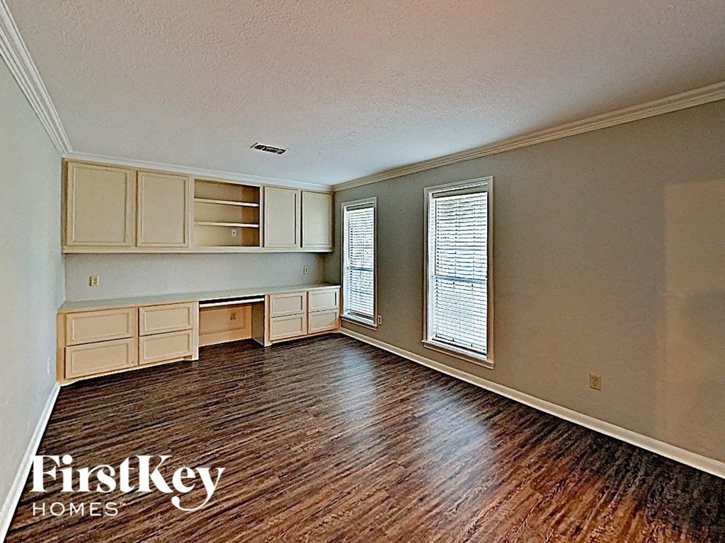an empty living room with wood floors and white cabinets