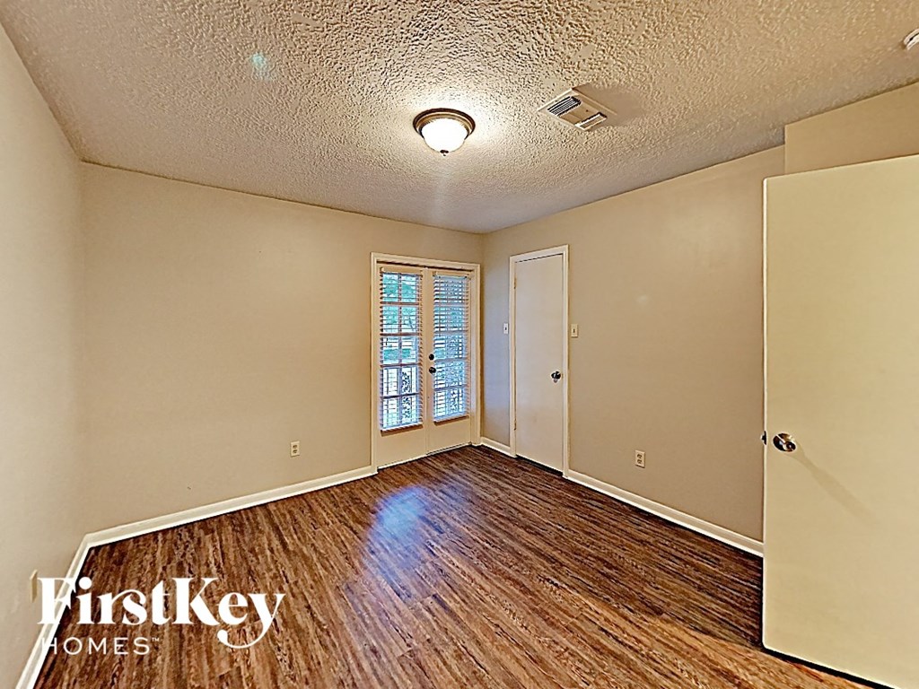 an empty living room with wood flooring and a window