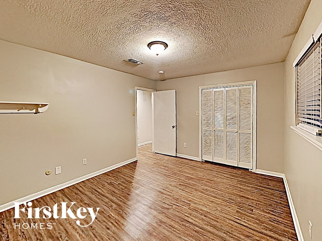 an empty living room with wood flooring and a door to a closet