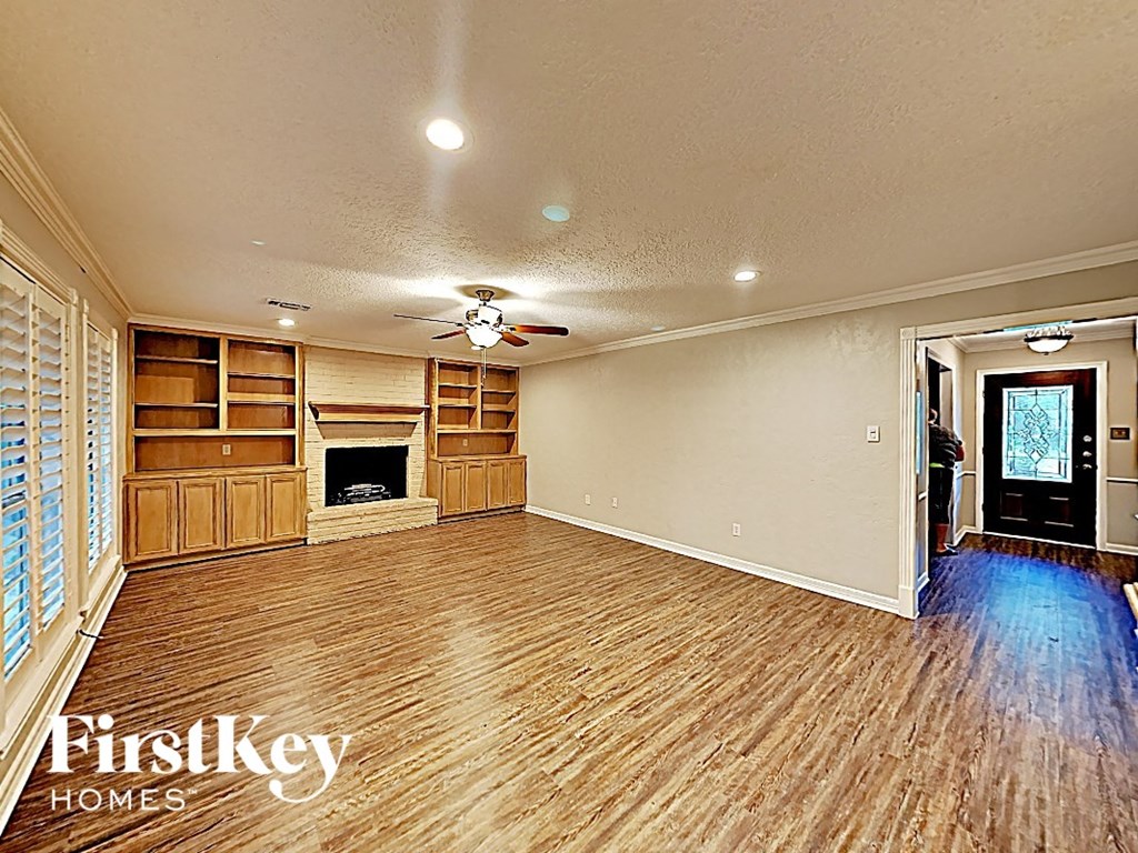 an empty living room with a fireplace and wooden floors
