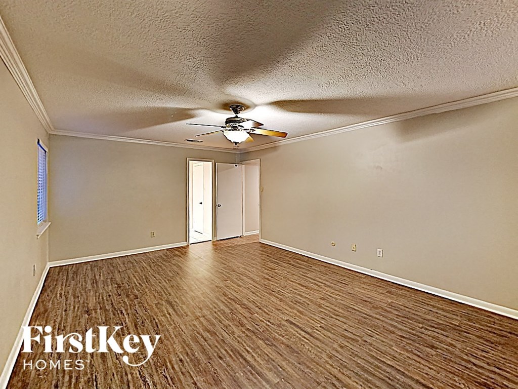 an empty living room with wood flooring and a ceiling fan