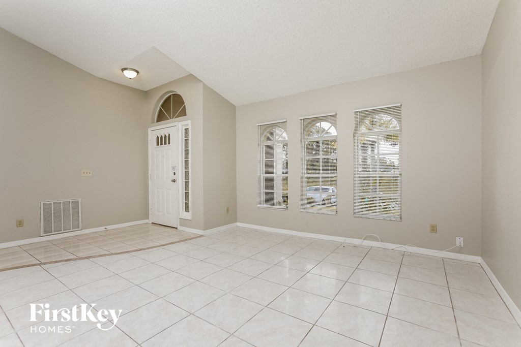 A spacious room with a white door and windows.