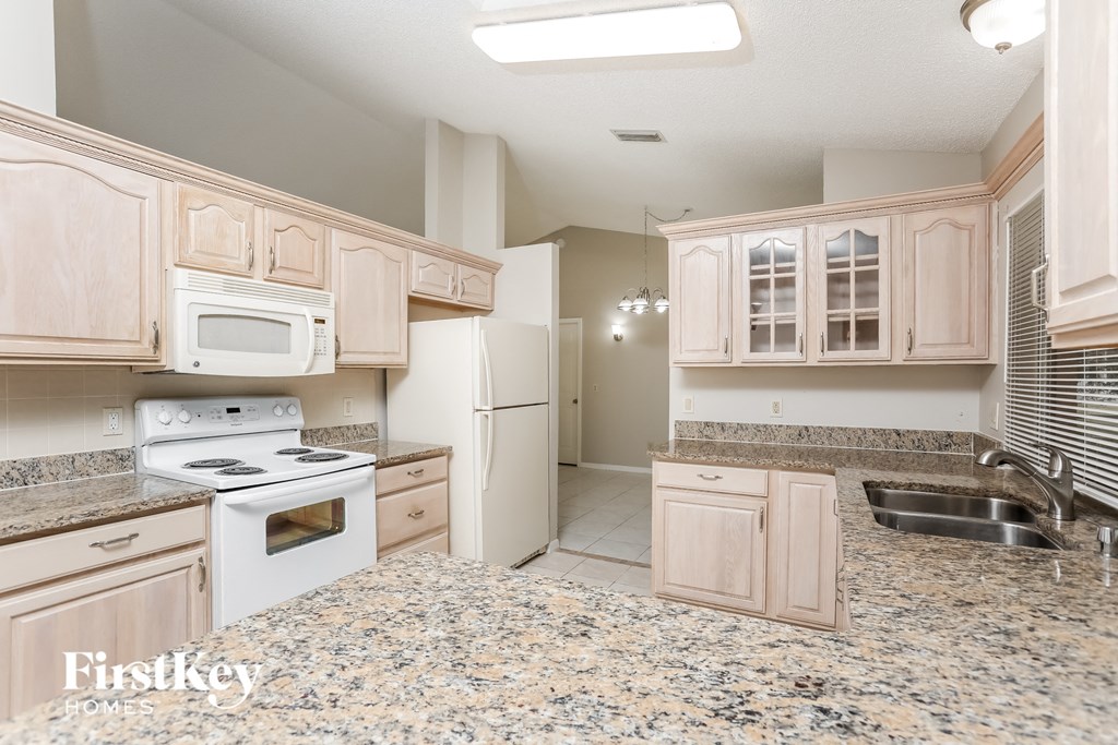 A kitchen with granite countertops and a refrigerator with the door open.