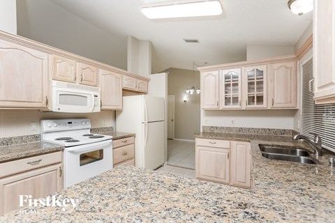 A kitchen with granite countertops and a refrigerator with the door open.