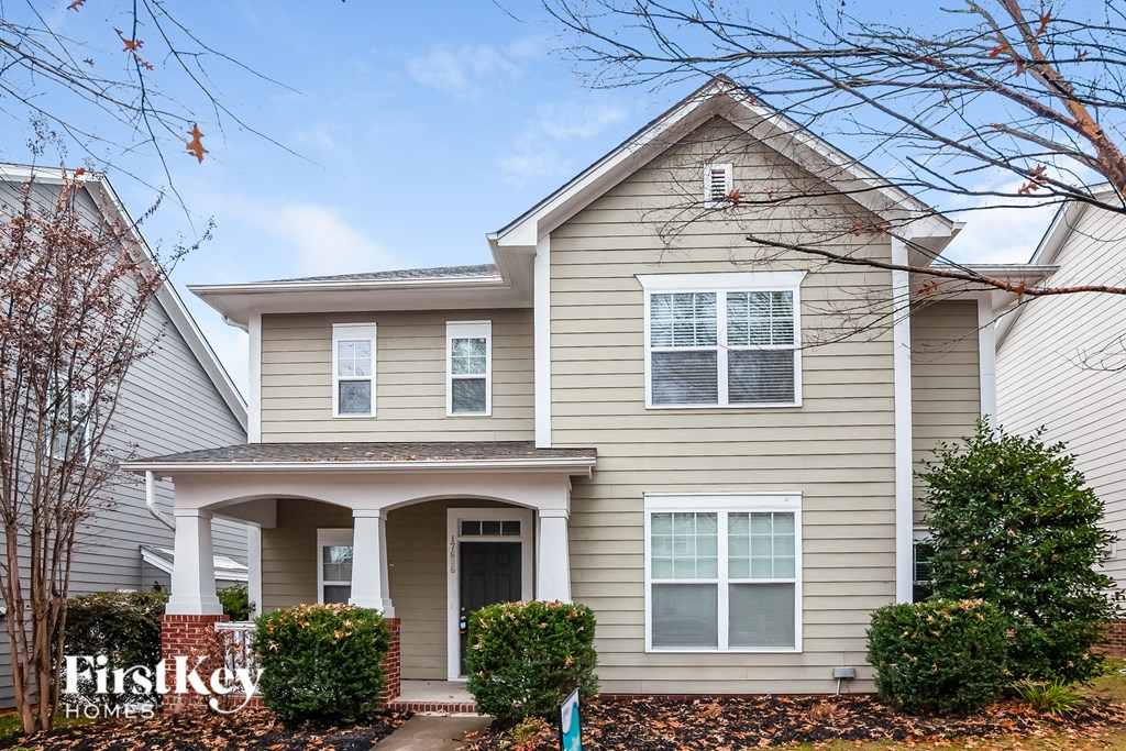 a beige house with a front porch on a sunny day