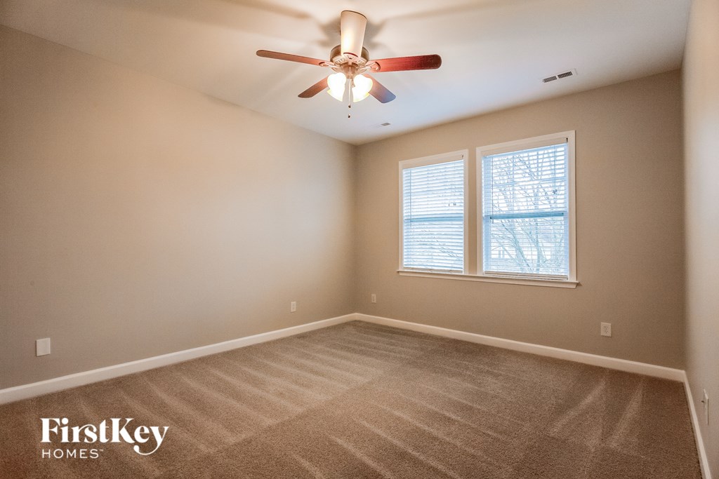 the master bedroom has a carpeted floor and a ceiling fan